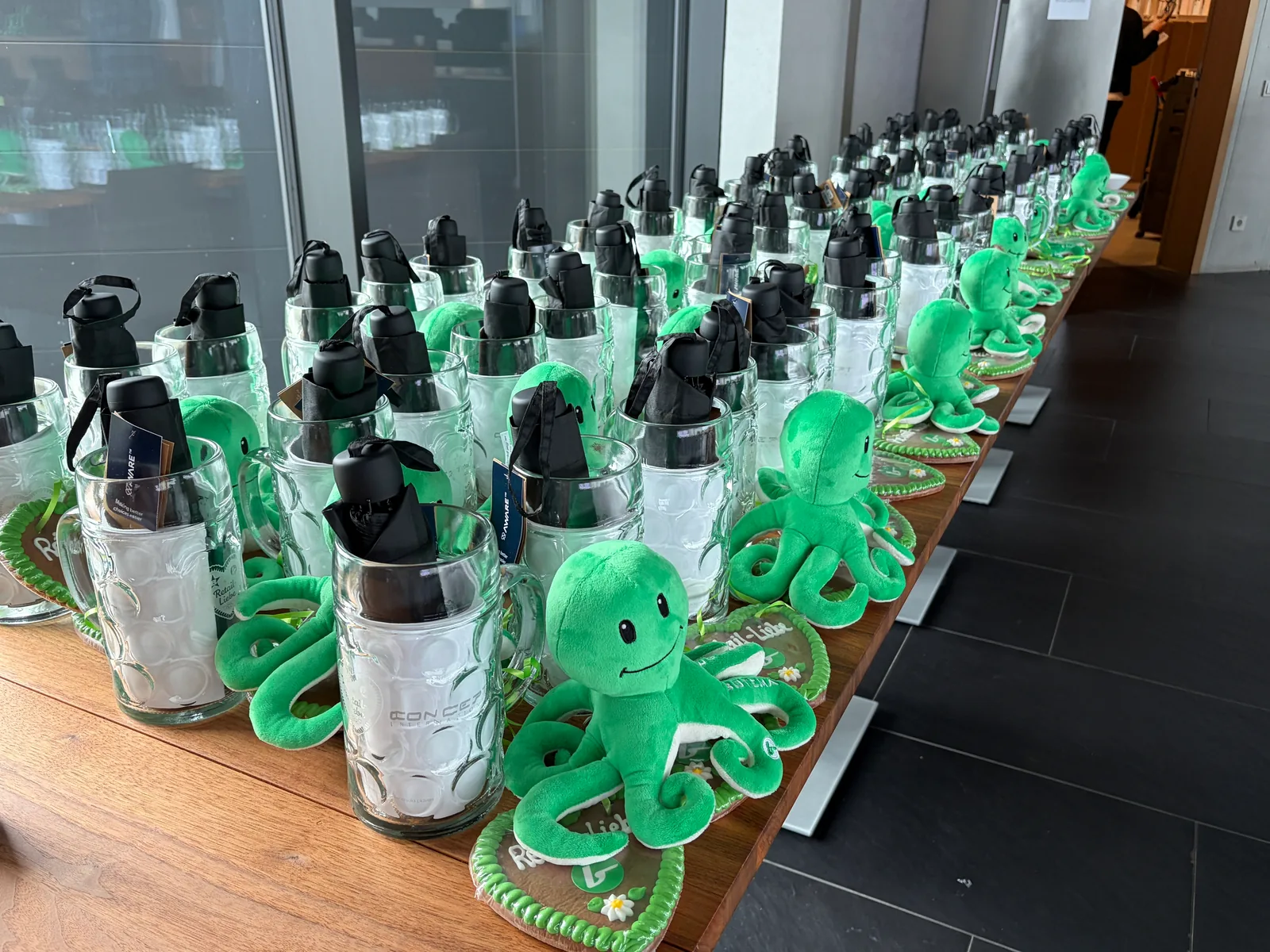 Gastgeschenke in Reihen: Glaskrüge mit schwarzen Taschenschirmen, grüne Plüsch-Kraken auf Lebkuchenherzen