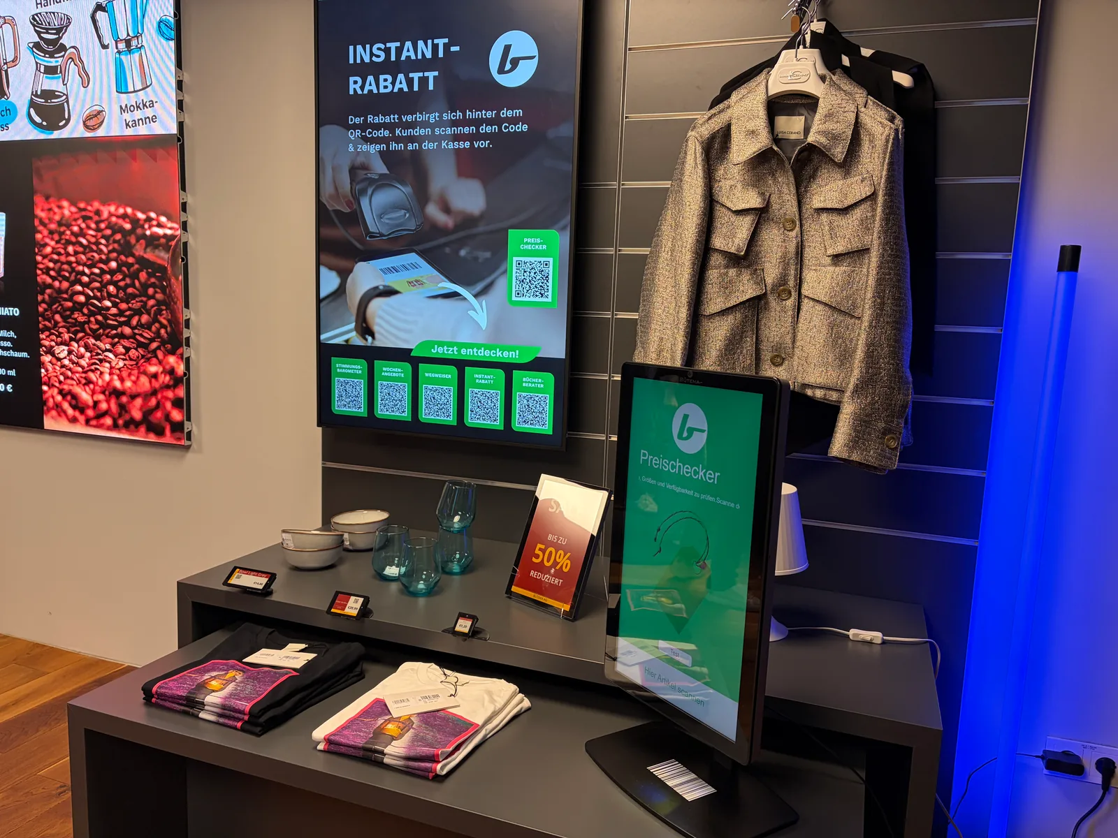 Showroom-Display mit Instant-Rabatt-Aktion, QR-Codes und Preischecker neben einer ausgestellten Jacke